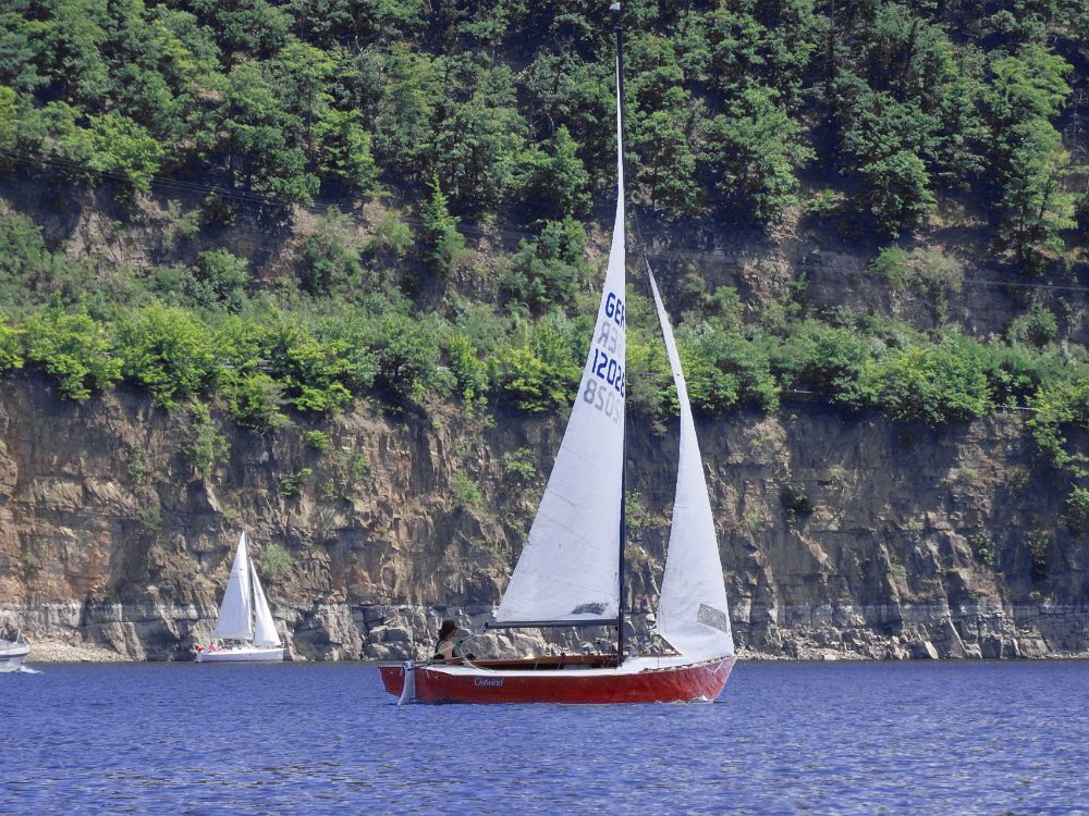 Segelsommer am Edersee. Die elegante Ostwind vor der Felswand bei Rehbach. Lightning aus Vollholz, oft Selbstbauten, werden in ihrer Heimat Amerika "Woodies" genannt