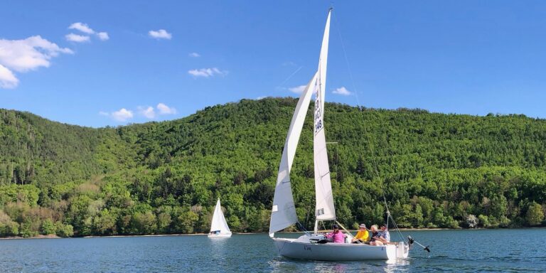 Ansegeln 2025. Start in die Segelsaison am Edersee. Die J22 des USC-Kassel segelt mit leichtem Wind Richtung Asel. Der 1. Mai bietet eine prächtige Kulisse.