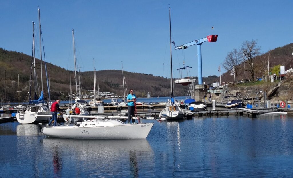 Boote einsetzen zum Saisonstart am Edersee. Die Varianta hängt noch am Kran während die J22 ihren Liegeplatz anläuft